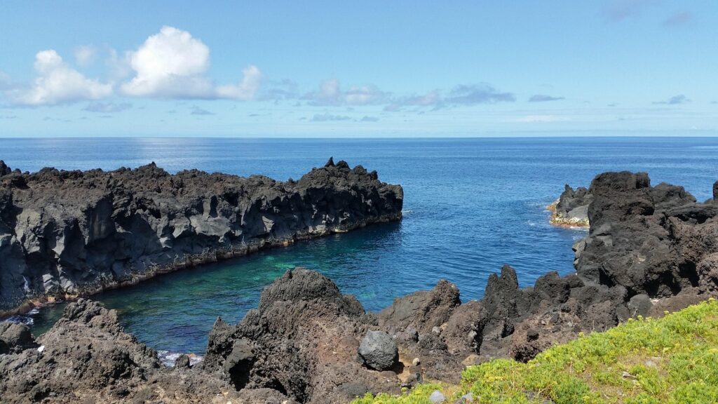 Pueblo tradicional en una faja de São Jorge con iglesia y hortensias azules, Azores