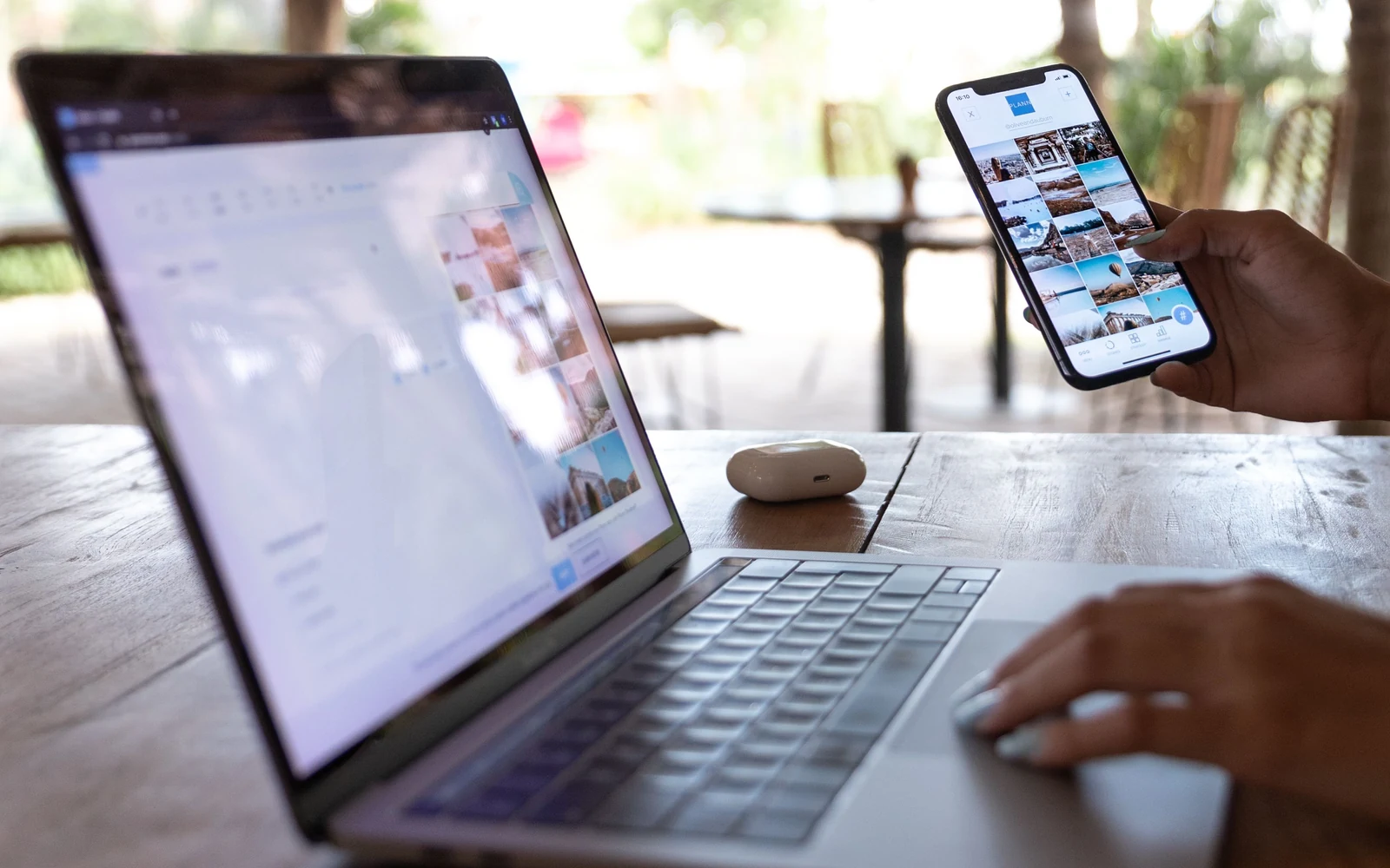 Pessoa a utilizar um portátil e um telemóvel numa mesa ao ar livre