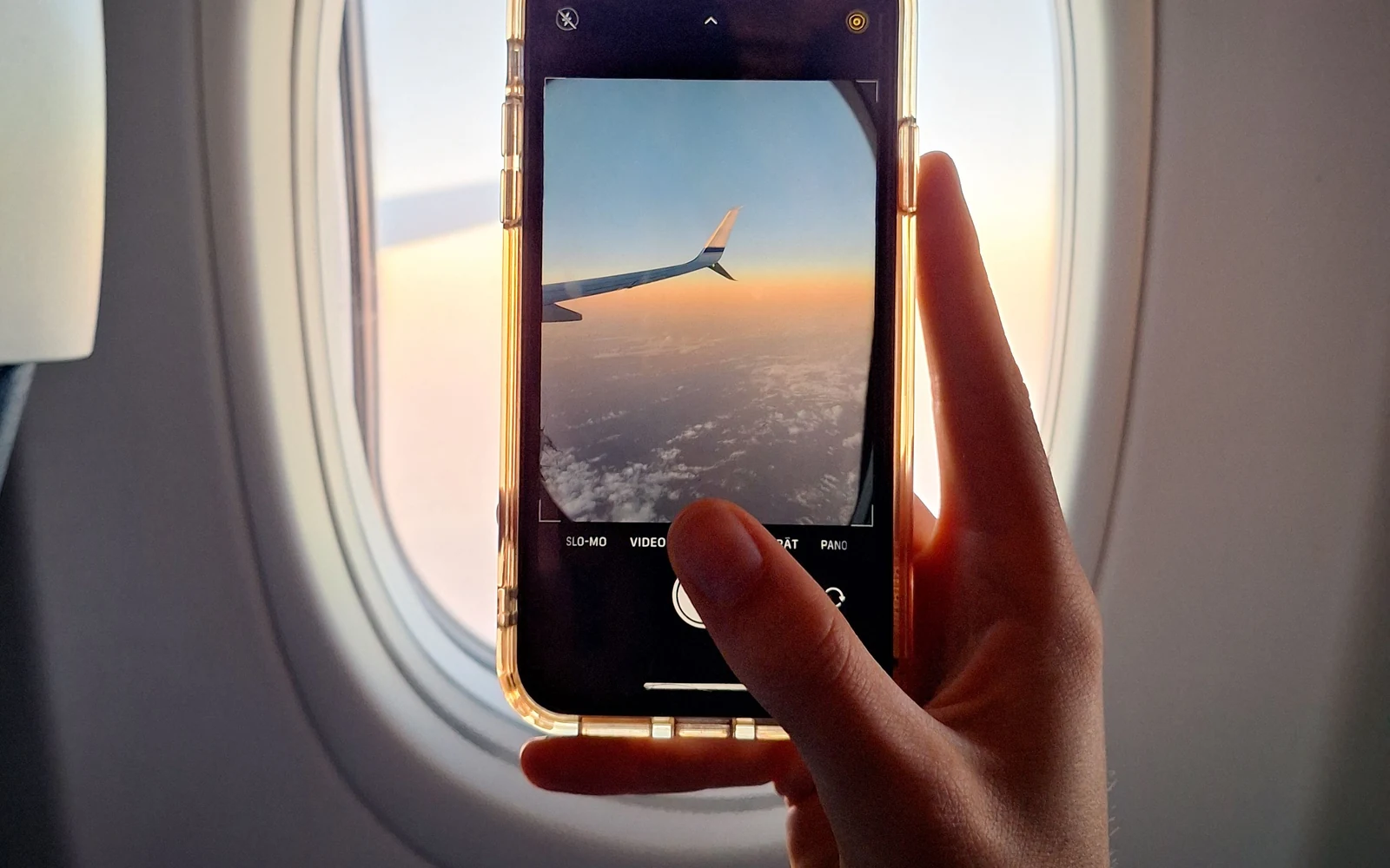 Telemóvel a fotografar a asa de um avião através da janela