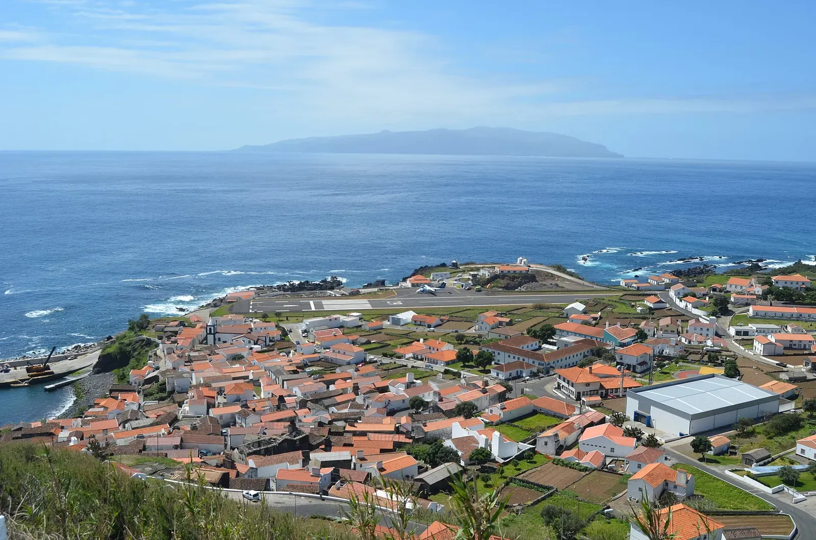 Vila do Corvo houses beside the sea with Flores in the background